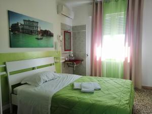 a bedroom with a green bed with a towel on it at GreenColors Hotel in Campalto