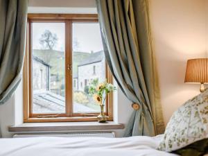 Un dormitorio con una ventana con un jarrón de flores en 3 Bed in Hartington 54215 en Hartington