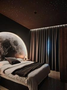 1 dormitorio con 1 cama grande y un mural del planeta en Star Room, en Ras al Khaimah