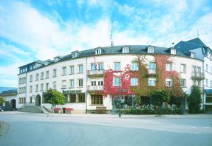 un grande edificio bianco con fiori ai lati di Hotel Kinnen a Berdorf