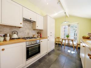 una cucina con armadi bianchi e piano cottura di 1 Bed in Evesham 55177 a Bretforton