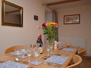 a wooden table with glasses and a vase of flowers at 3 Bed in Wells 55232 in Chewton Mendip