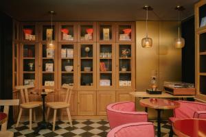 un restaurante con sillas rosas, mesas y armarios en La Dépendance, en París