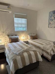 sypialnia z 2 łóżkami i oknem w obiekcie Kookaburra Cottage w mieście Bowral