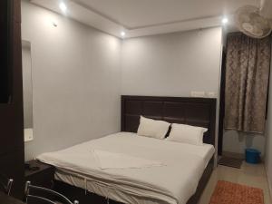 una camera da letto con un grande letto con lenzuola bianche di HOTEL IMF a Patna