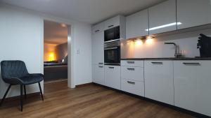 a kitchen with white cabinets and a chair and a sink at City Appartement Cologne North in Dormagen
