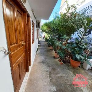 a hallway with potted plants and an open door at Like home Διαμέρισμα κοντά στο ΤΕΙ και στο κέντρο in Lamía