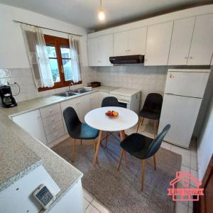 een keuken met een witte tafel en stoelen en een wastafel bij Like home Διαμέρισμα κοντά στο ΤΕΙ και στο κέντρο in Lamía