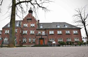 a large red brick building with a clock tower at City Appartement Cologne North in Dormagen