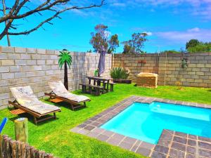 podwórko z basenem, stołem i krzesłami w obiekcie Theescombe Accomodation w mieście Port Elizabeth