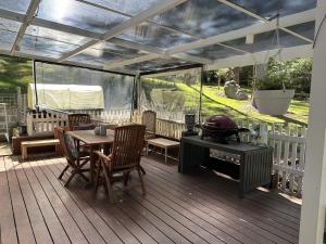 eine Terrasse mit einem Grill, einem Tisch und Stühlen in der Unterkunft Kookaburra Cottage in Bowral