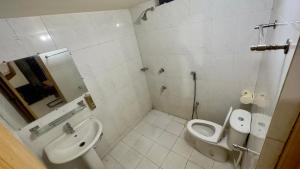 a white bathroom with a toilet and a sink at Appayan Guest House Baridhara (Bhagyakula Building) in Dhaka