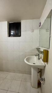 a white bathroom with a sink and a mirror at Appayan Guest House Baridhara (Bhagyakula Building) in Dhaka