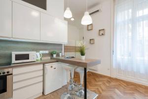 una cucina con armadi bianchi e un tavolo con forno a microonde di Szent Istvan ter 4 Next to Basilica a 1 BedRoom a Budapest