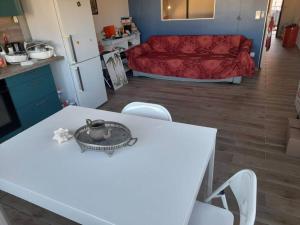 a kitchen and living room with a white table and chairs at Les pieds dans l’eau in Baie Nettle