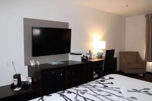 a hotel room with a bed and a desk and a television at Wingate by Wyndham Kings Bay Naval Base in Kingsland