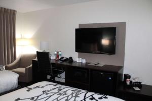 a hotel room with a desk with a television on the wall at Wingate by Wyndham Kings Bay Naval Base in Kingsland