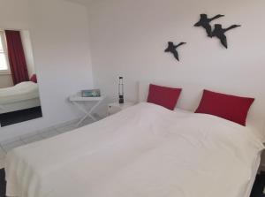 a bedroom with a white bed with birds on the wall at Apartmentvermittlung Mehr als Meer - Objekt 18 in Niendorf