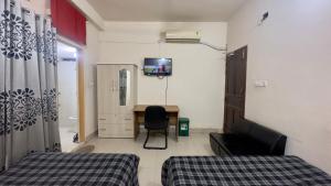 a room with two beds and a desk and a television at Appayan Guest House Baridhara (Bhagyakula Building) in Dhaka