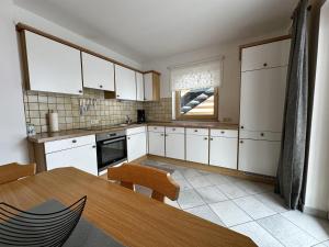 uma cozinha com armários brancos e uma mesa de madeira em Apartment Troger em Fieberbrunn