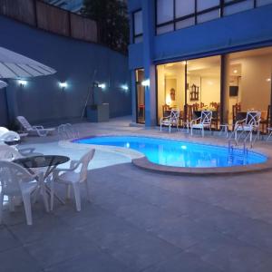 una piscina con sillas, una mesa y un patio en Hotel Alcala del Rio, en Santiago