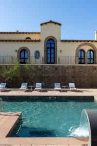 una casa con una piscina con sillas y un edificio en Hotel Le Dune Piscinas, en Ingurtosu