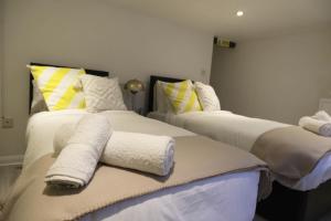 two beds with towels on them in a room at Stylish 4 Bed Home in Aylesbury, Buckinghamshire in Buckinghamshire