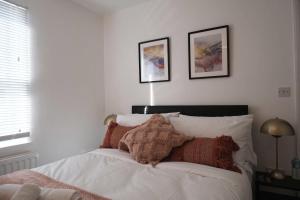 - une chambre avec un lit blanc et des oreillers dans l'établissement Stylish 4 Bed Home in Aylesbury, Buckinghamshire, à Buckinghamshire