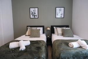 a bedroom with two beds with towels on them at Stylish 4 Bed Home in Aylesbury, Buckinghamshire in Buckinghamshire