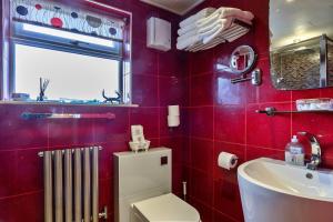 a red bathroom with a toilet and a sink at Finest Retreats - Treknow Summerhut in Tintagel +21 photos