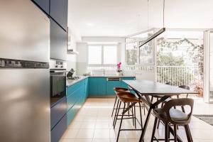 una cocina con armarios azules y una mesa con sillas en Appartements BnBIsrael - Hovevei Tsiyon Jasmin, en Tel Aviv