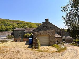 an old stone house with a garage at Brookside in Langthwaite