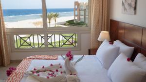 a bedroom with a bed with a view of the beach at Oyster Bay Beach Suites in Abu Dabbab