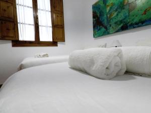 a white bed with white towels on top of it at Duplex acogedor con gran terraza en pleno centro de Sevilla! in Seville