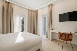 biała sypialnia z łóżkiem, biurkiem i telewizorem w obiekcie Unico w mieście Sassari