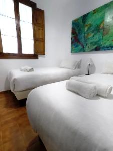 2 letti in una camera con pareti e finestre bianche di Duplex acogedor con gran terraza en pleno centro de Sevilla! a Siviglia