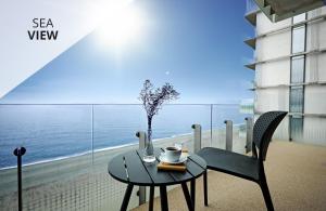 een tafel en stoelen op een balkon met uitzicht op de oceaan bij Miramare Magnetic Beach Hotel in Kobuleti