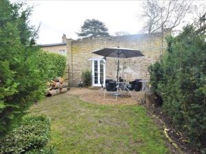 une terrasse avec un parasol en face d'une maison dans l'établissement 1 bed in Beccles 65080, à Beccles