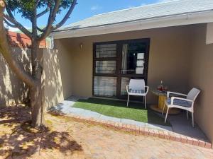 a house with two chairs and a table and a window at Bellville Self Catering in Cape Town