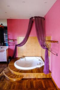 a bath tub in a bathroom with pink walls at La Tourelle in Pullay