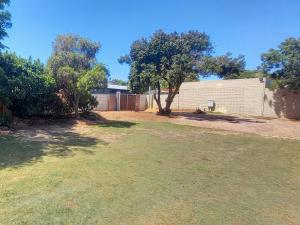 a yard with a fence and trees and a building at Bellville Self Catering in Cape Town