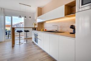 a kitchen with white cabinets and a counter with stools at Apartments Corcovado in Vodice