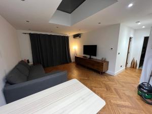 a living room with a couch and a flat screen tv at Hassocks House - Modern Detached 2 Bedroom House in Streatham in Streatham Vale