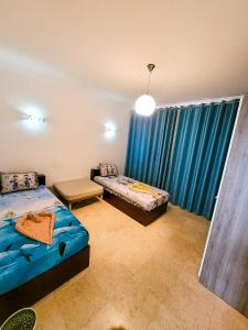 New Marina Hurghada Suite في الغردقة: غرفة نوم بسريرين ونافذة ذات ستائر زرقاء