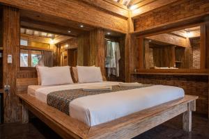 Cama grande en habitación con paredes de madera en Jawa House Private Villas, en Gili Trawangan