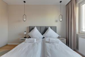 una camera con 2 letti con lenzuola e cuscini bianchi di NORDBYHUS Apartamenty Seaside Baltea Park a Danzica