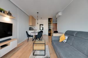 a living room with a gray couch and a table at NORDBYHUS Apartamenty Seaside Baltea Park in Gdańsk