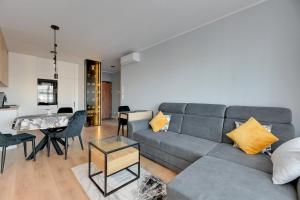 un soggiorno con divano grigio e tavolo di NORDBYHUS Apartamenty Seaside Baltea Park a Danzica