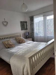 a white bed in a bedroom with a window at Riverside Bungalow - direct river access! in Ystradgynlais