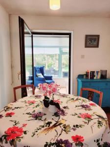 a dining room table with a floral table cloth with flowers at Riverside Bungalow - direct river access! in Ystradgynlais